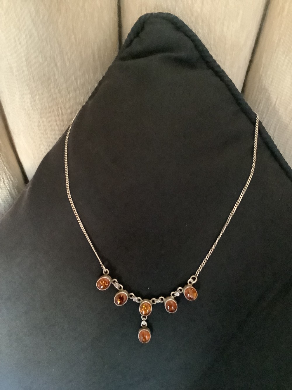 A fine silver chain necklace featuring six bezel-set oval cognac amber cabochons arranged in a central drop configuration. View IV