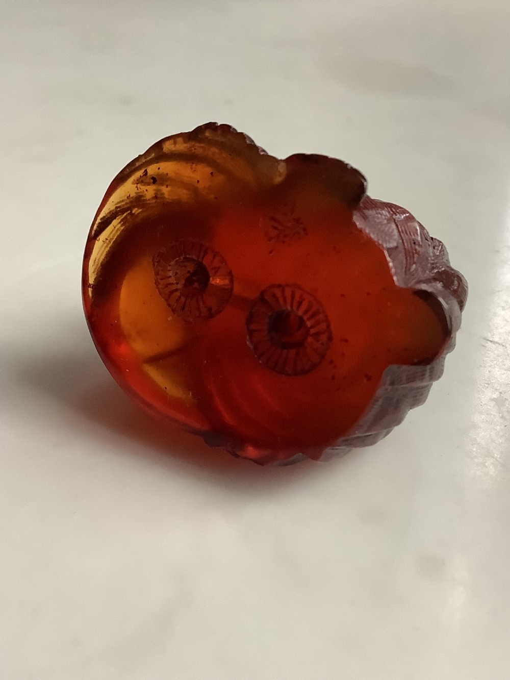 A small, translucent cherry amber carving depicting a curled sleeping cat with incised fur details. View VI