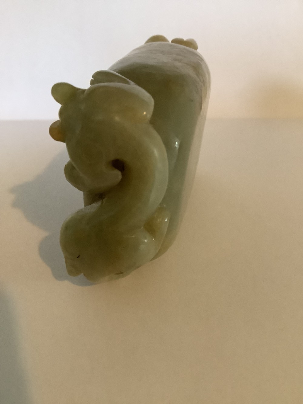 A hollowed pale green jade brush washer featuring high-relief dragon carvings along the outer edges and natural russet undertones. View VII