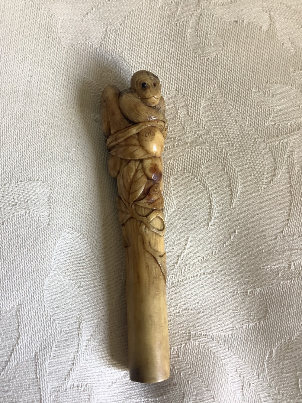 An antique Japanese stag horn parasol handle hand-carved with a monkey figure among leaf and branch motifs. View III