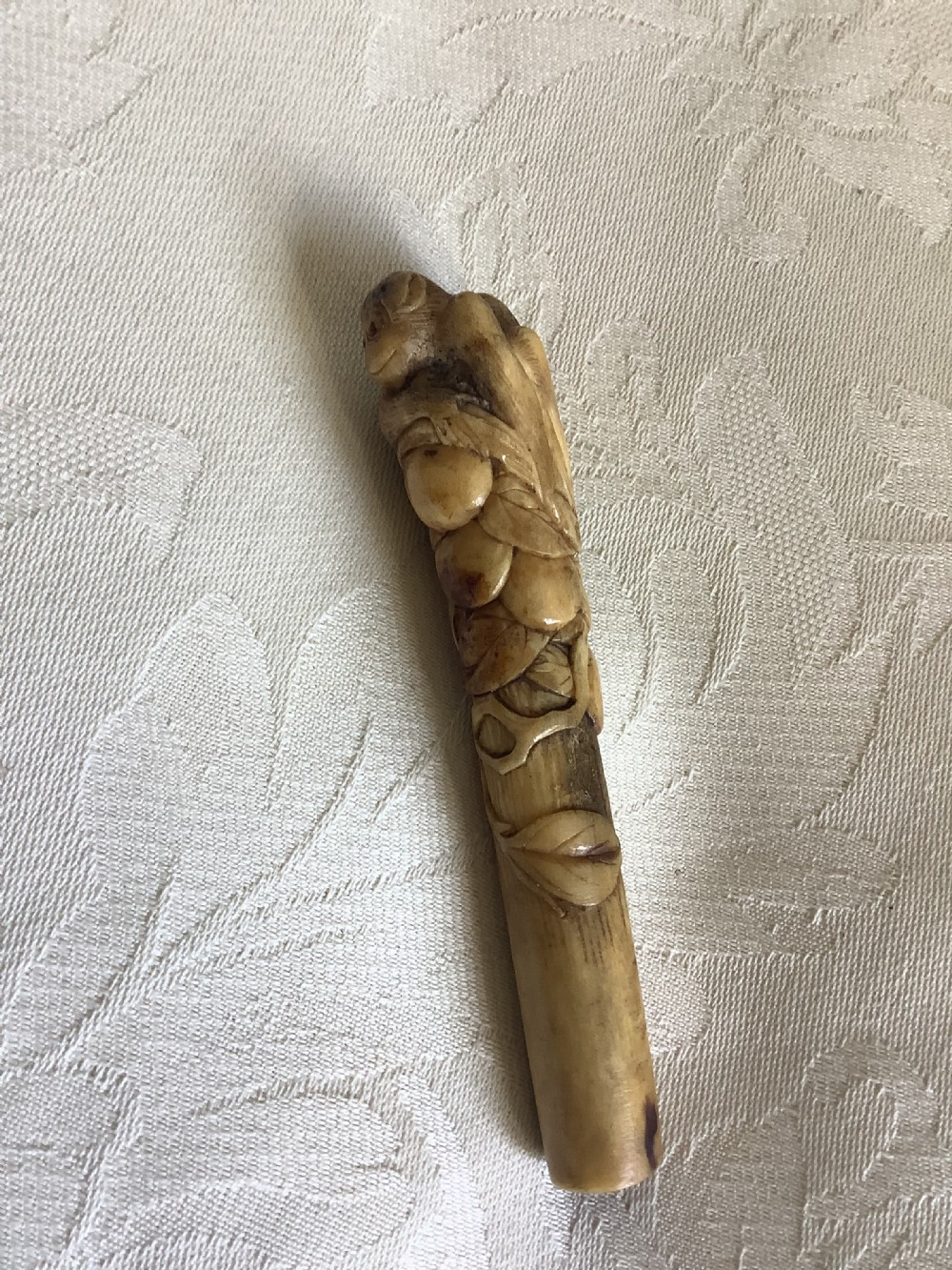 An antique Japanese stag horn parasol handle hand-carved with a monkey figure among leaf and branch motifs. View IV