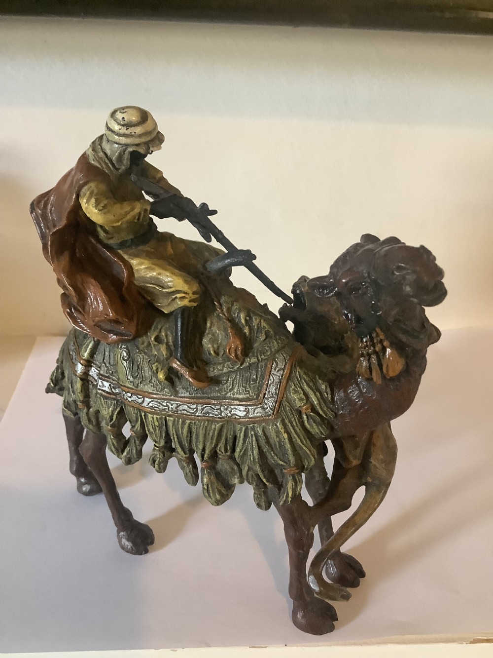 A cold painted bronze sculpture depicting a draped Arabic rider holding a rifle atop a camel. View II