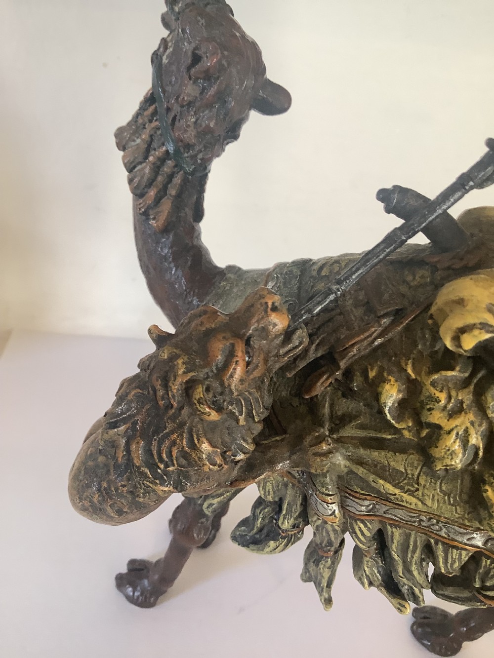 A cold painted bronze sculpture depicting a draped Arabic rider holding a rifle atop a camel. View III