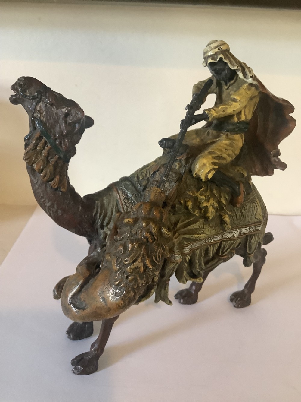 A cold painted bronze sculpture depicting a draped Arabic rider holding a rifle atop a camel. View IV