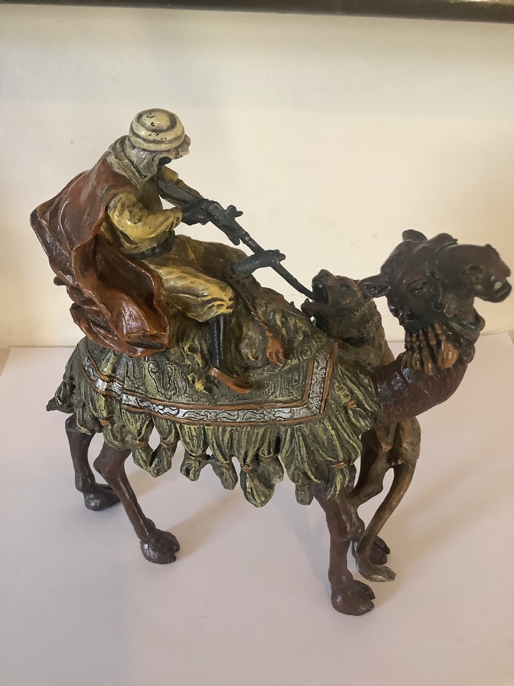 A cold painted bronze sculpture depicting a draped Arabic rider holding a rifle atop a camel. View V