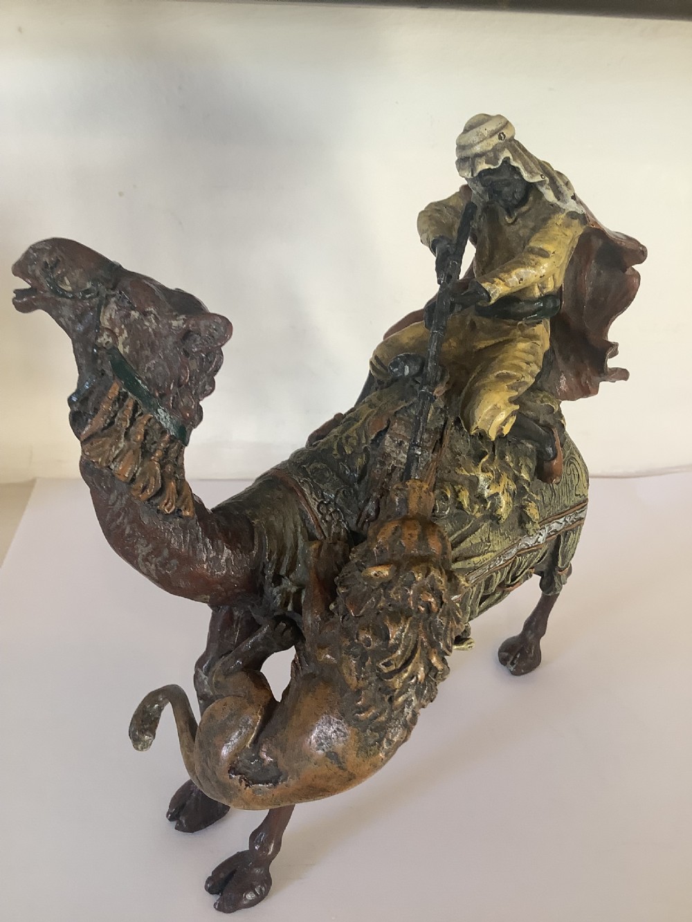 A cold painted bronze sculpture depicting a draped Arabic rider holding a rifle atop a camel. View VI