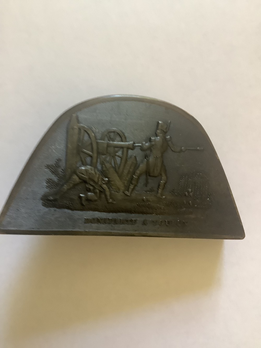 A dark brown pressed horn snuff box shaped like a bicorn hat with a relief scene depicting Napoleon at Toulon. View V