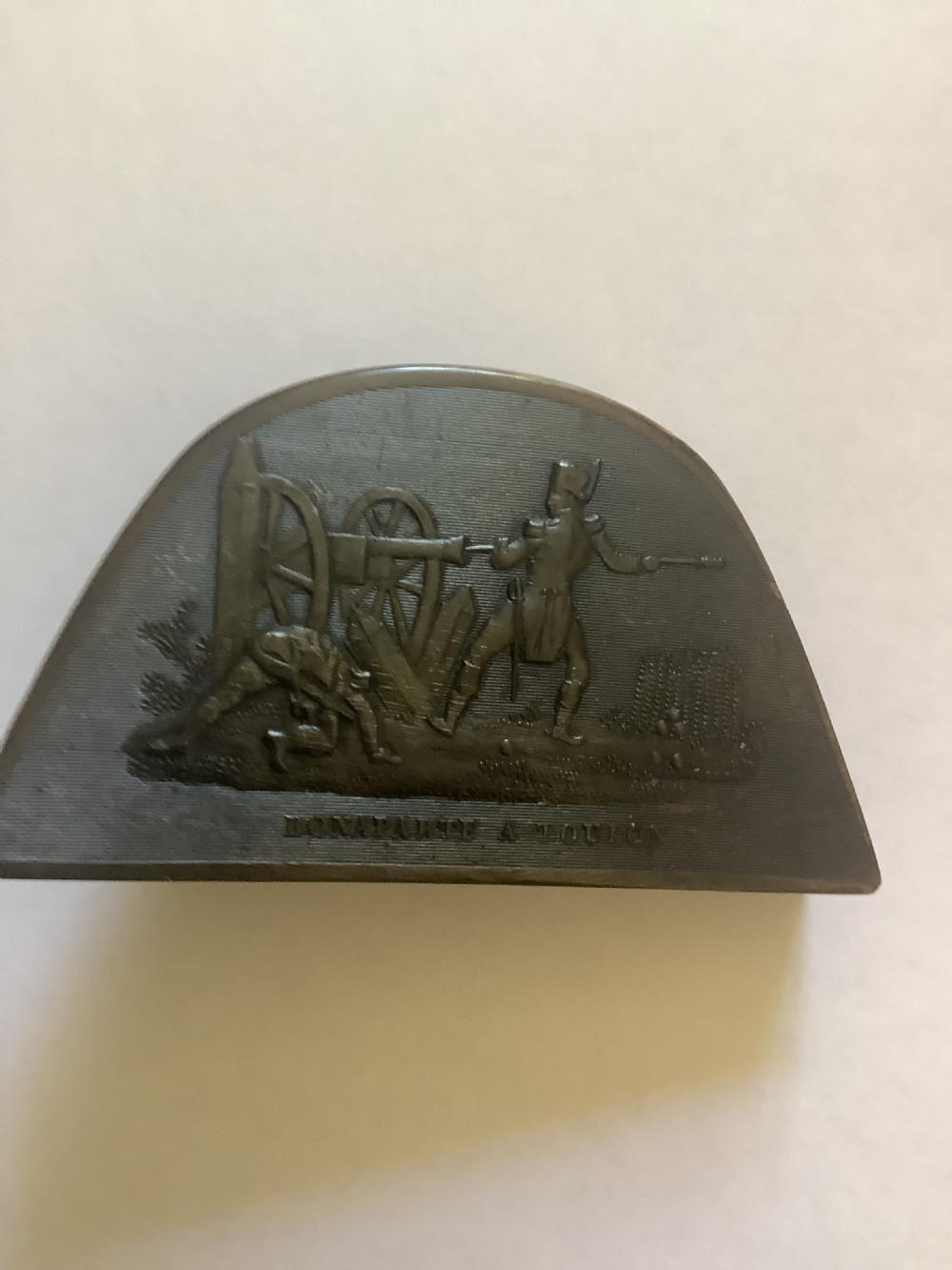 A dark brown pressed horn snuff box shaped like a bicorn hat with a relief scene depicting Napoleon at Toulon. View VII