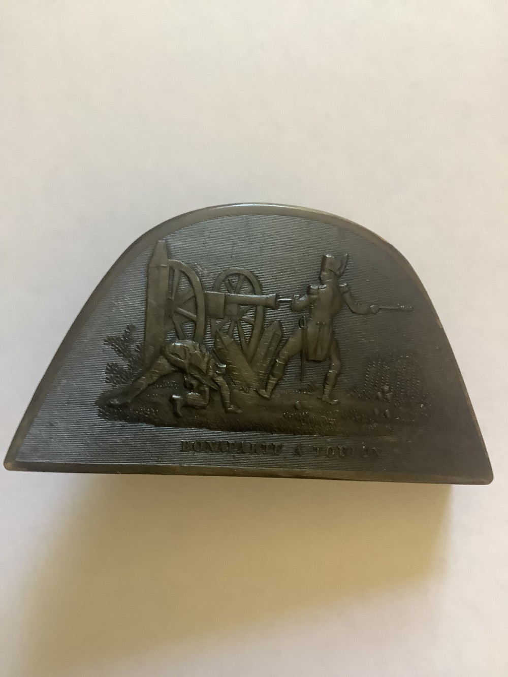 A dark brown pressed horn snuff box shaped like a bicorn hat with a relief scene depicting Napoleon at Toulon. View VIII