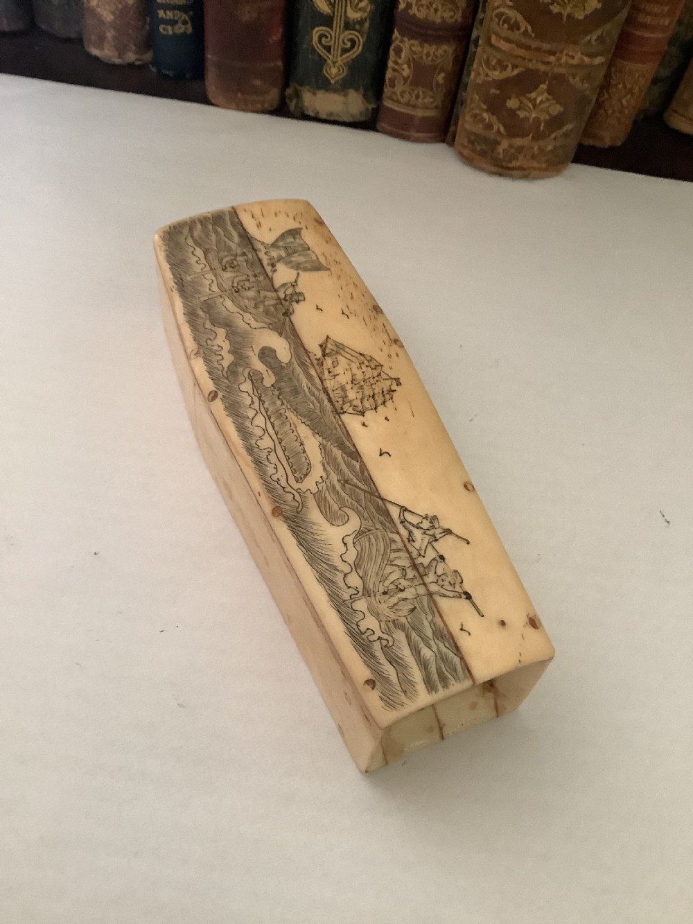 A cream-coloured bone coffin box featuring etched scrimshaw depictions of a whaling scene, boats, and ocean waves on the lid. View III