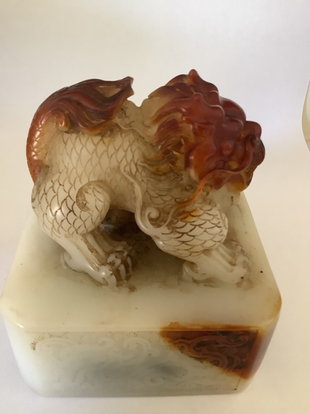 A carved cream and russet jade-style Chinese desk seal featuring a detailed guardian lion finial atop a square base. View II
