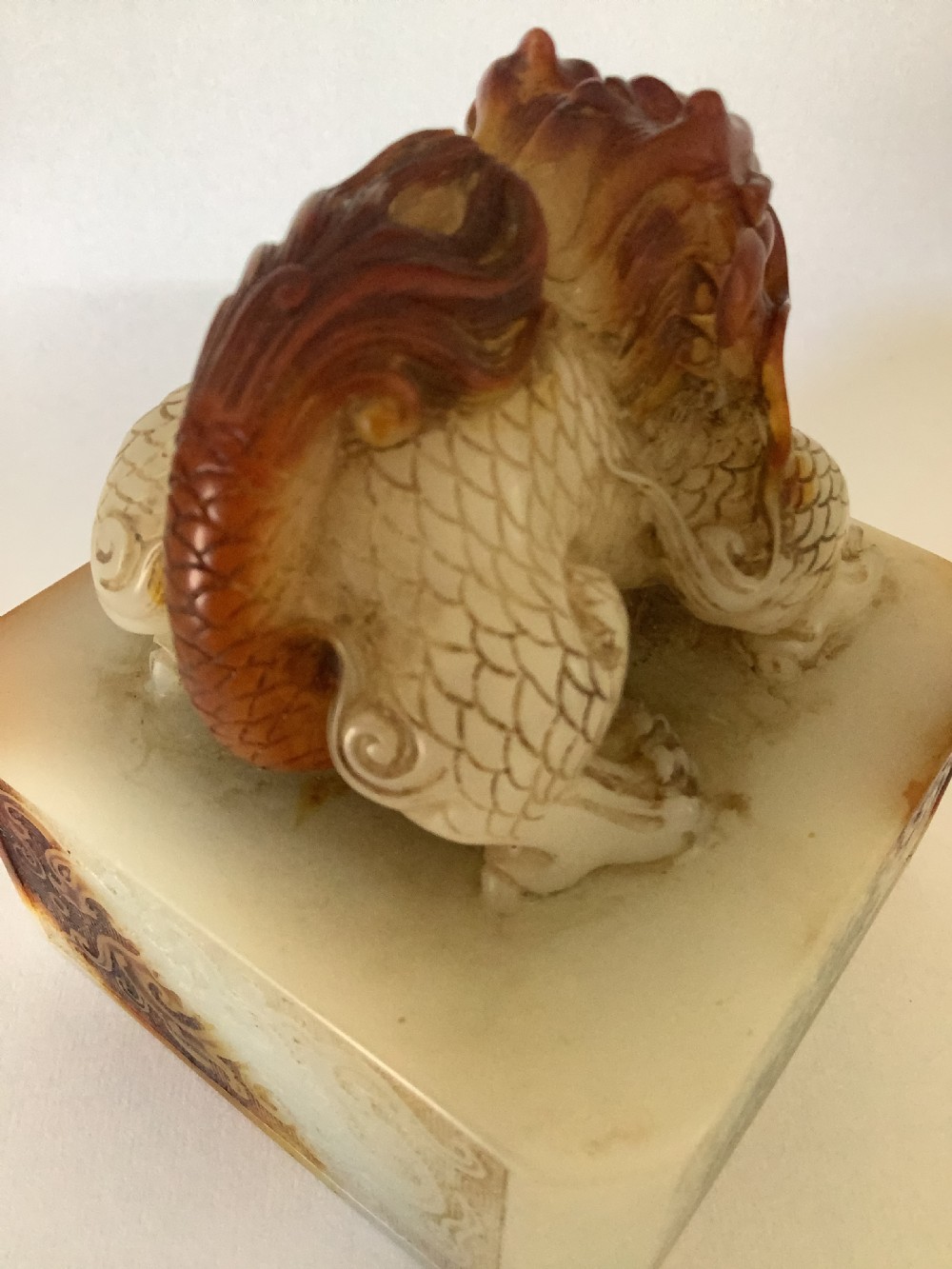 A carved cream and russet jade-style Chinese desk seal featuring a detailed guardian lion finial atop a square base. View IV