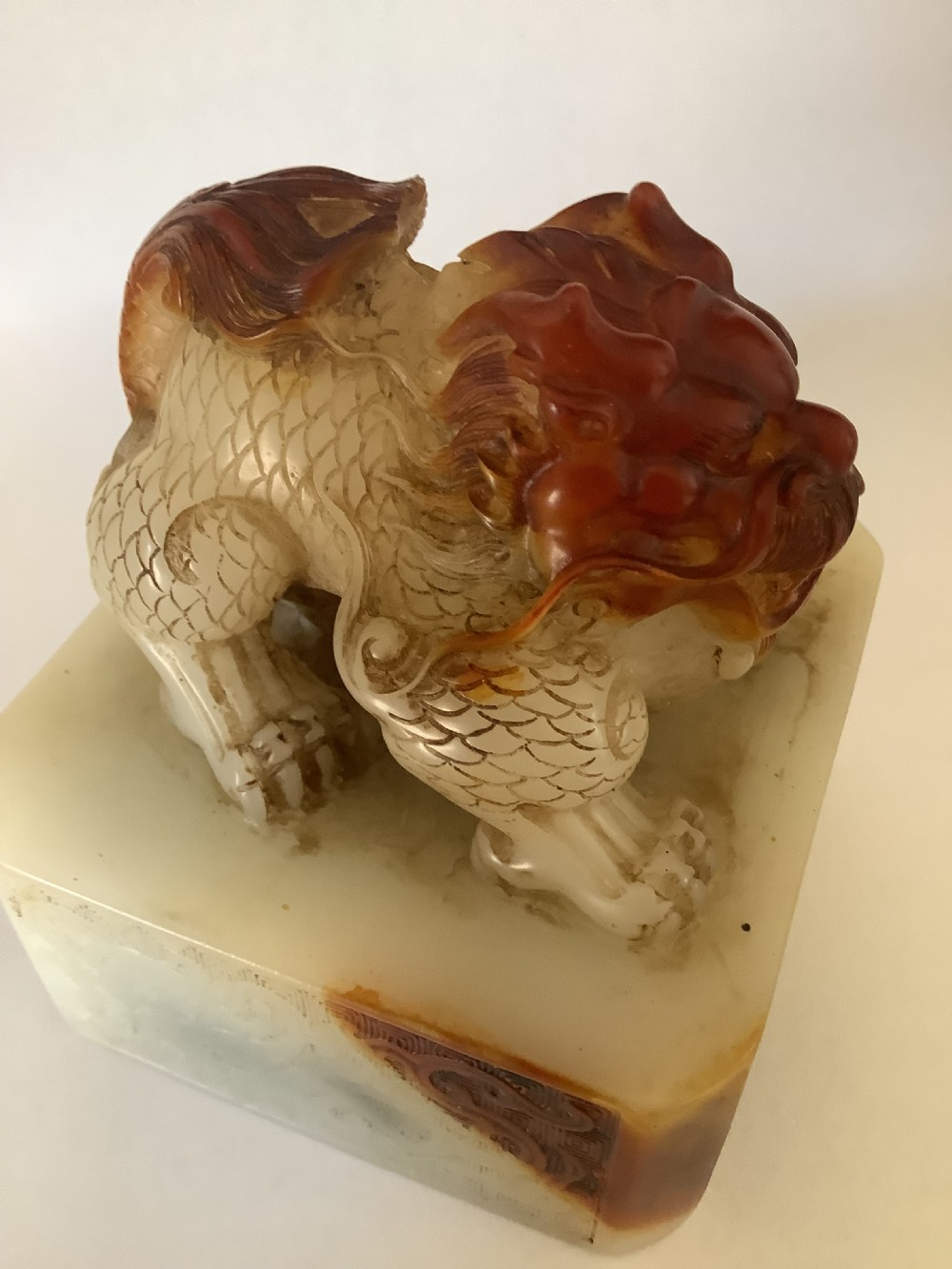 A carved cream and russet jade-style Chinese desk seal featuring a detailed guardian lion finial atop a square base. View V