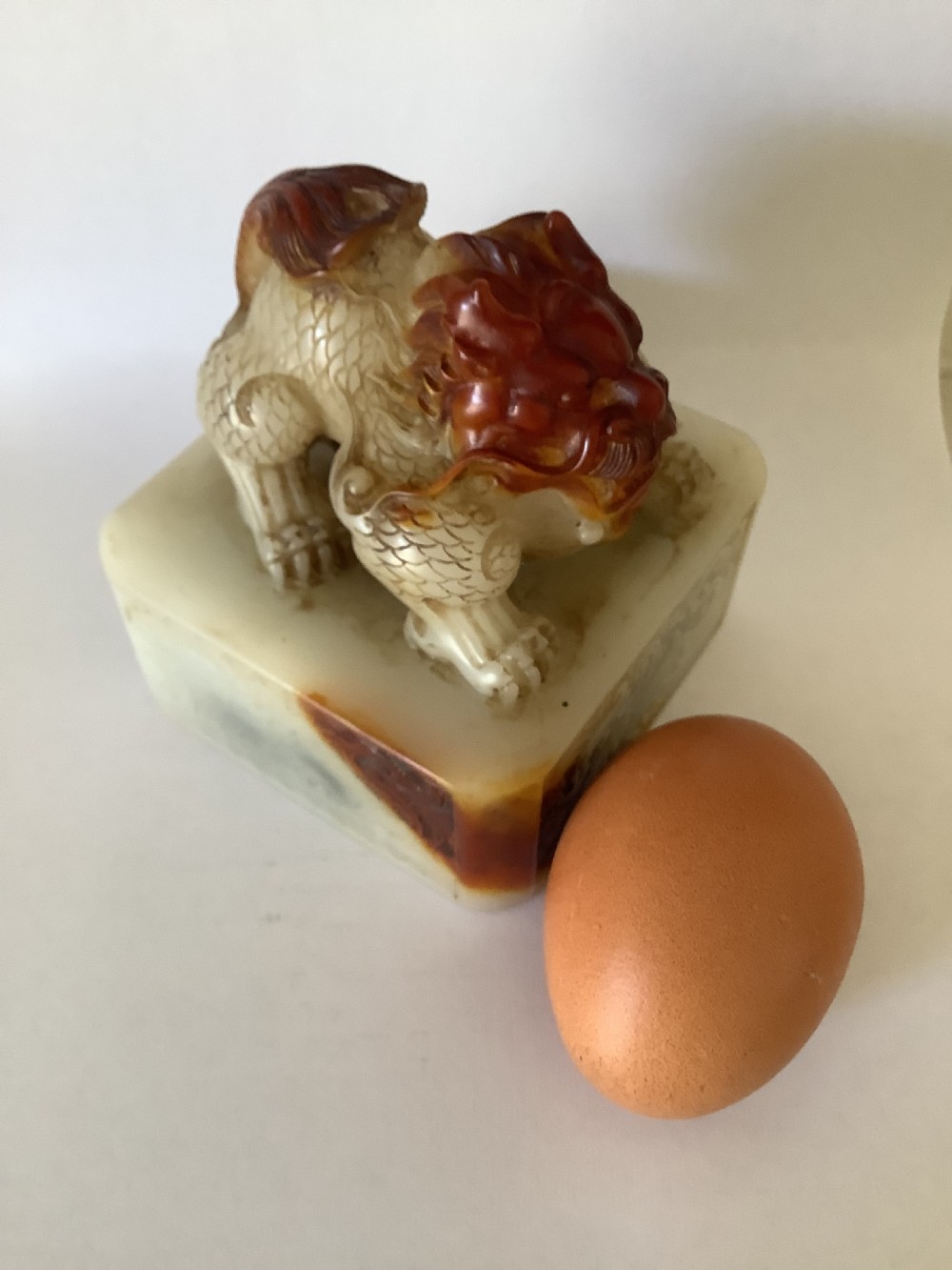 A carved cream and russet jade-style Chinese desk seal featuring a detailed guardian lion finial atop a square base. View VI