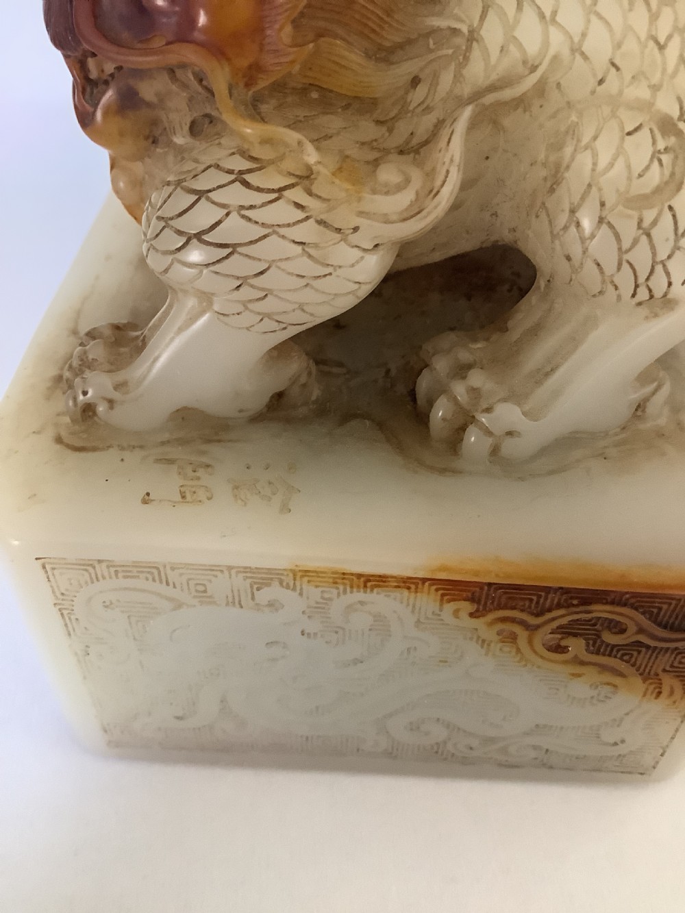 A carved cream and russet jade-style Chinese desk seal featuring a detailed guardian lion finial atop a square base. View IX