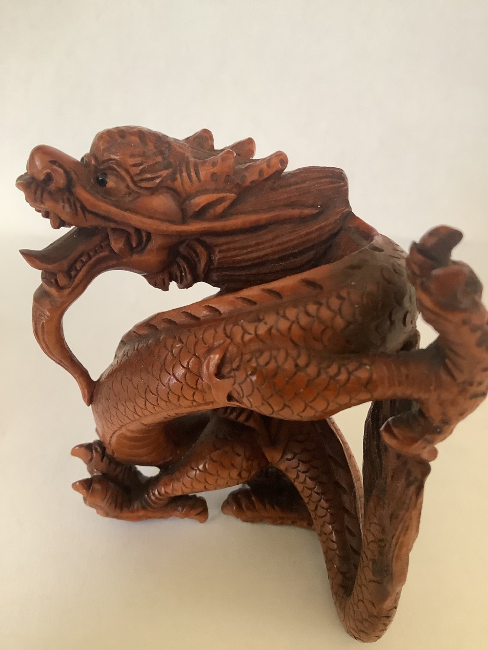 A finely detailed Japanese boxwood carving depicting a coiled dragon with an open mouth and carved scales.