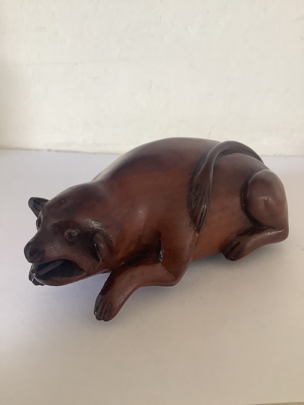 A hand-carved wooden snuff box sculpted in the form of a recumbent animal with a smooth brown finish. View II