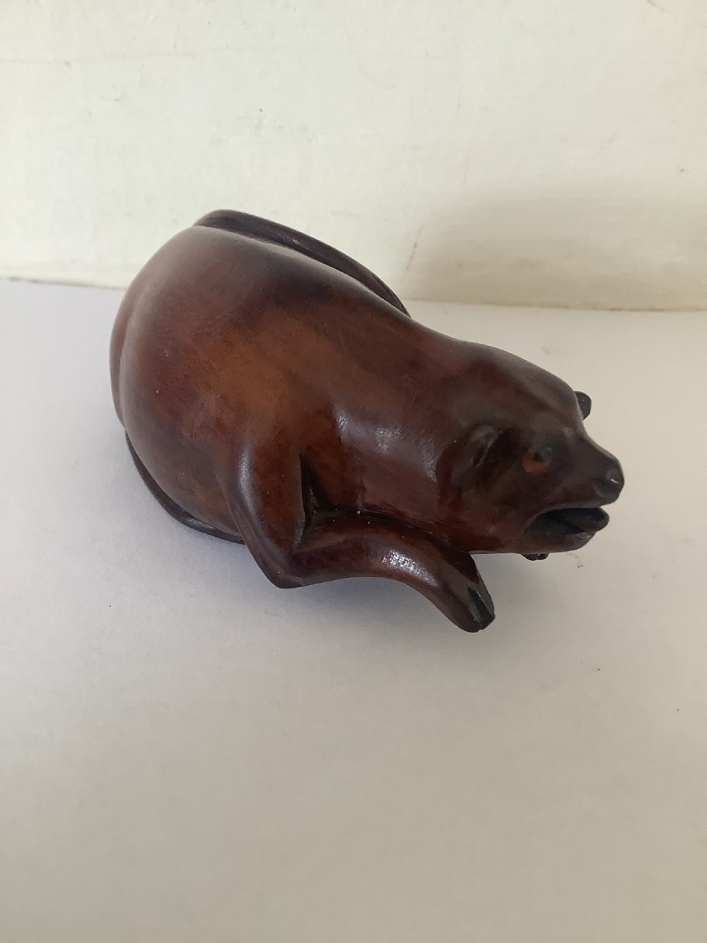 A hand-carved wooden snuff box sculpted in the form of a recumbent animal with a smooth brown finish. View III