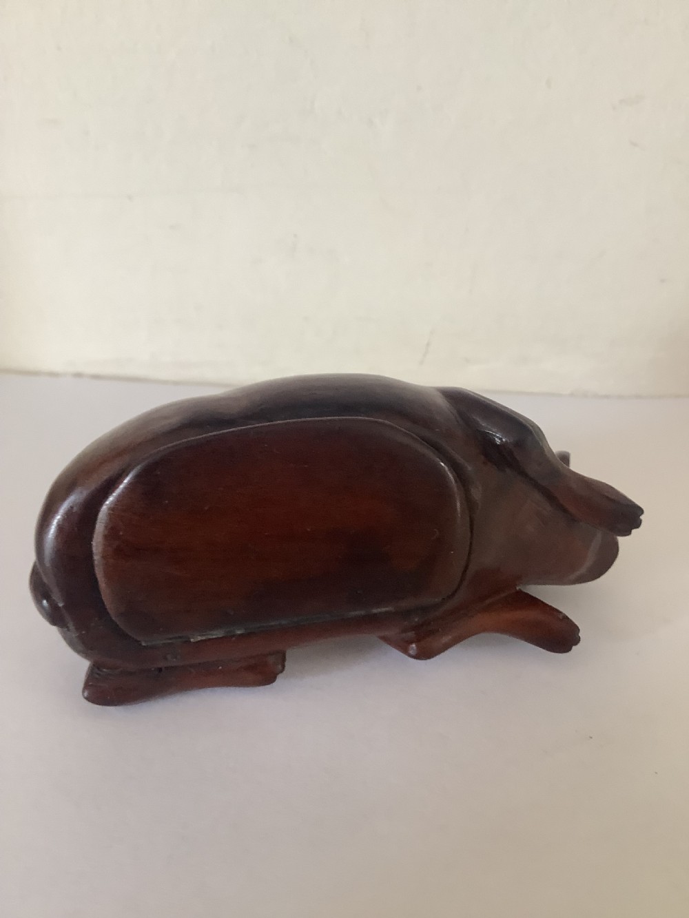 A hand-carved wooden snuff box sculpted in the form of a recumbent animal with a smooth brown finish. View VII