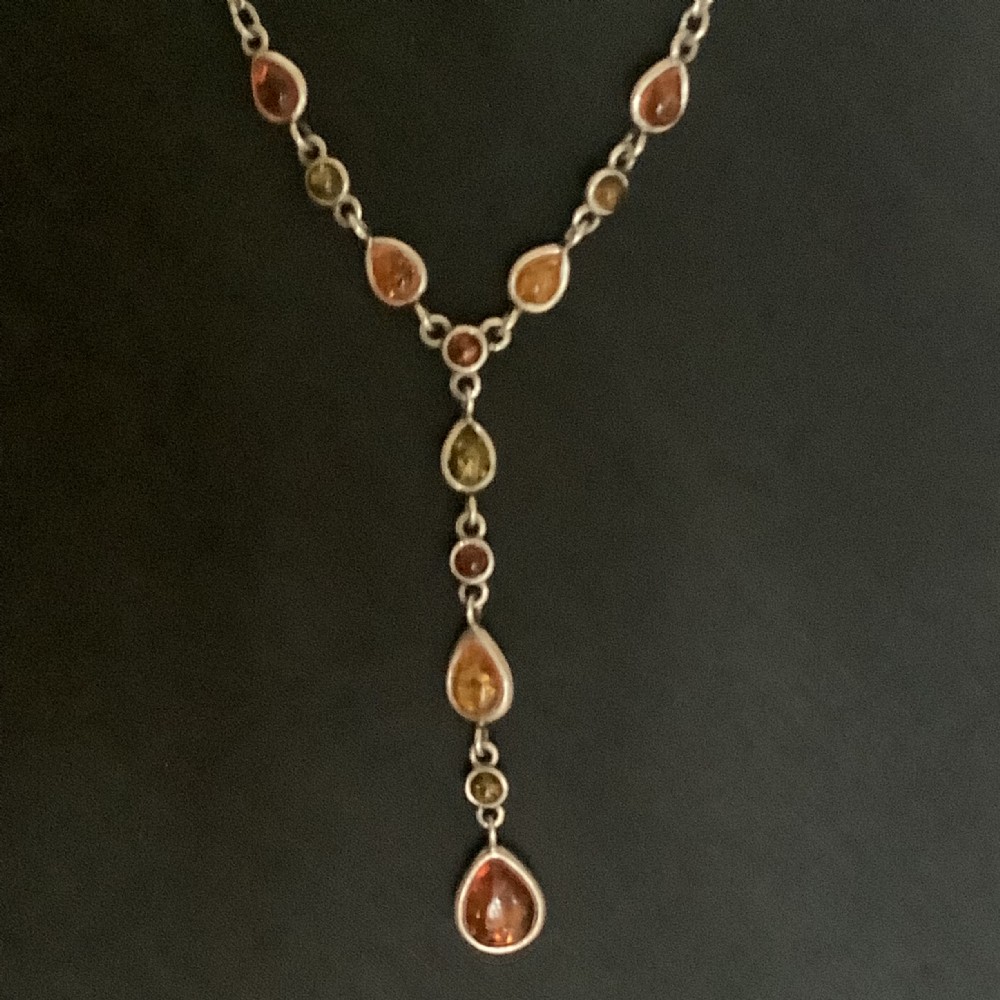 A silver Y-style chain necklace featuring bezel-set amber cabochons in shades of orange, yellow, and green arranged in a central cascading drop.