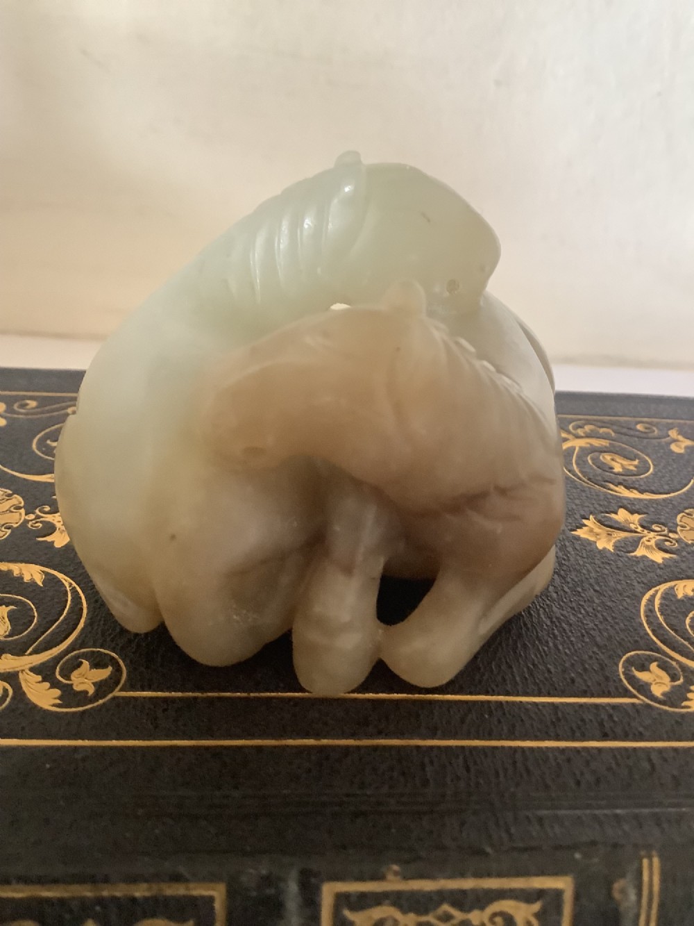 A hardstone carving depicting two recumbent horses crafted in pale celadon green stone. View II