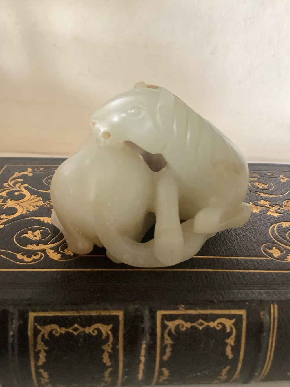 A hardstone carving depicting two recumbent horses crafted in pale celadon green stone. View III