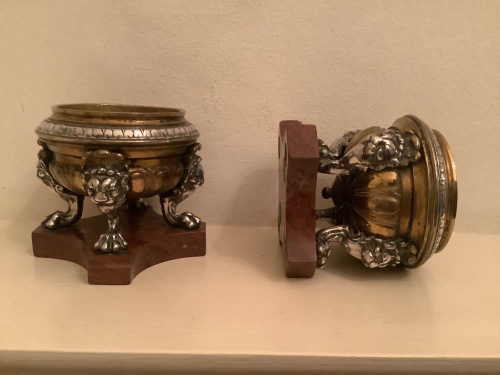 A pair of circular bronze and silvered metal tazzas featuring lion monopodia legs and resting on shaped red marble bases. View IV