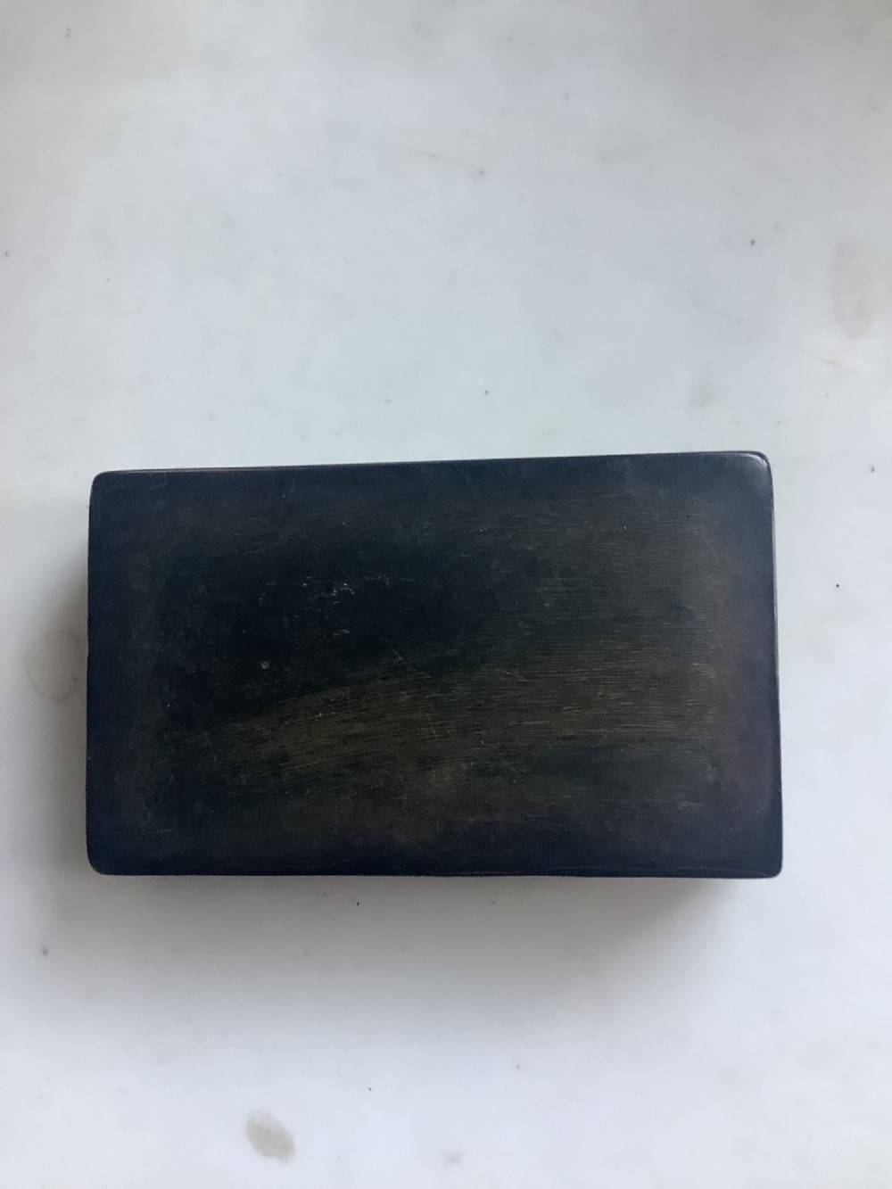 A rectangular dark brown pressed horn snuff box displaying a moulded relief of a biblical scene with figures and a French inscription on the top lid. View III