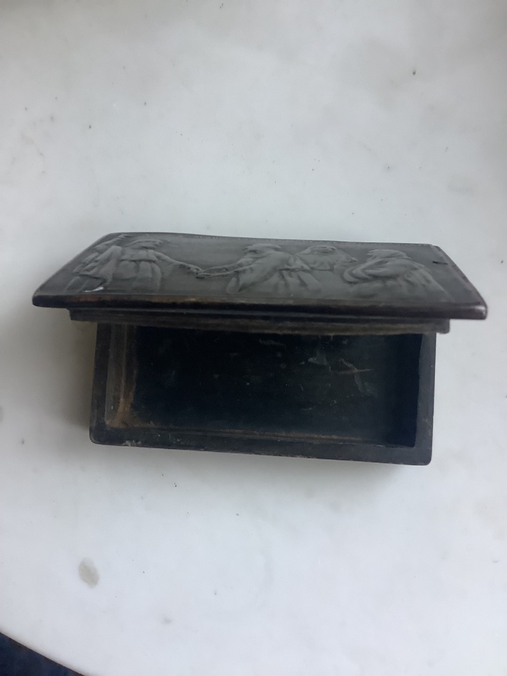 A rectangular dark brown pressed horn snuff box displaying a moulded relief of a biblical scene with figures and a French inscription on the top lid. View IV