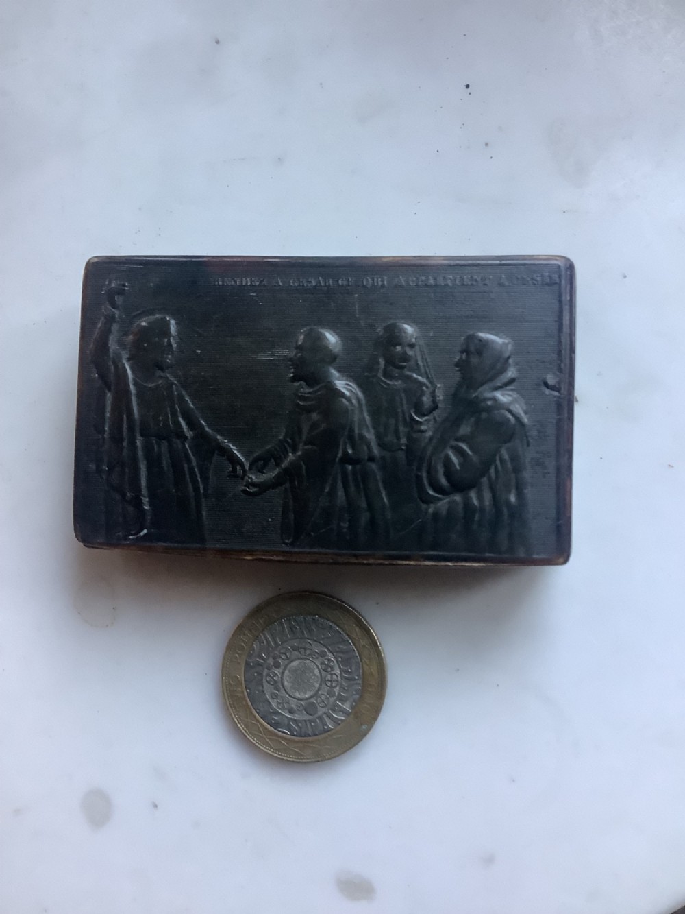 A rectangular dark brown pressed horn snuff box displaying a moulded relief of a biblical scene with figures and a French inscription on the top lid. View VI