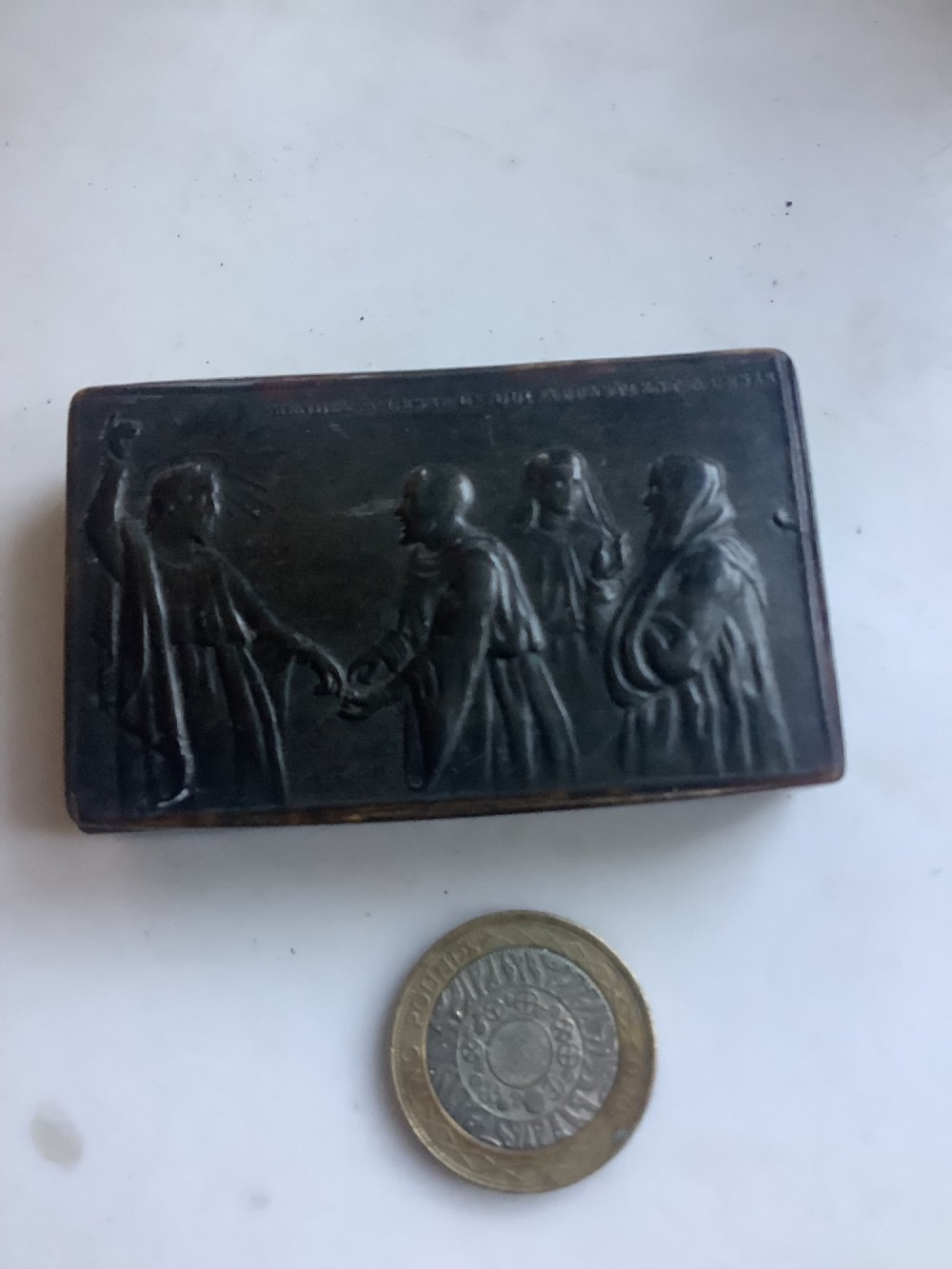 A rectangular dark brown pressed horn snuff box displaying a moulded relief of a biblical scene with figures and a French inscription on the top lid. View VII