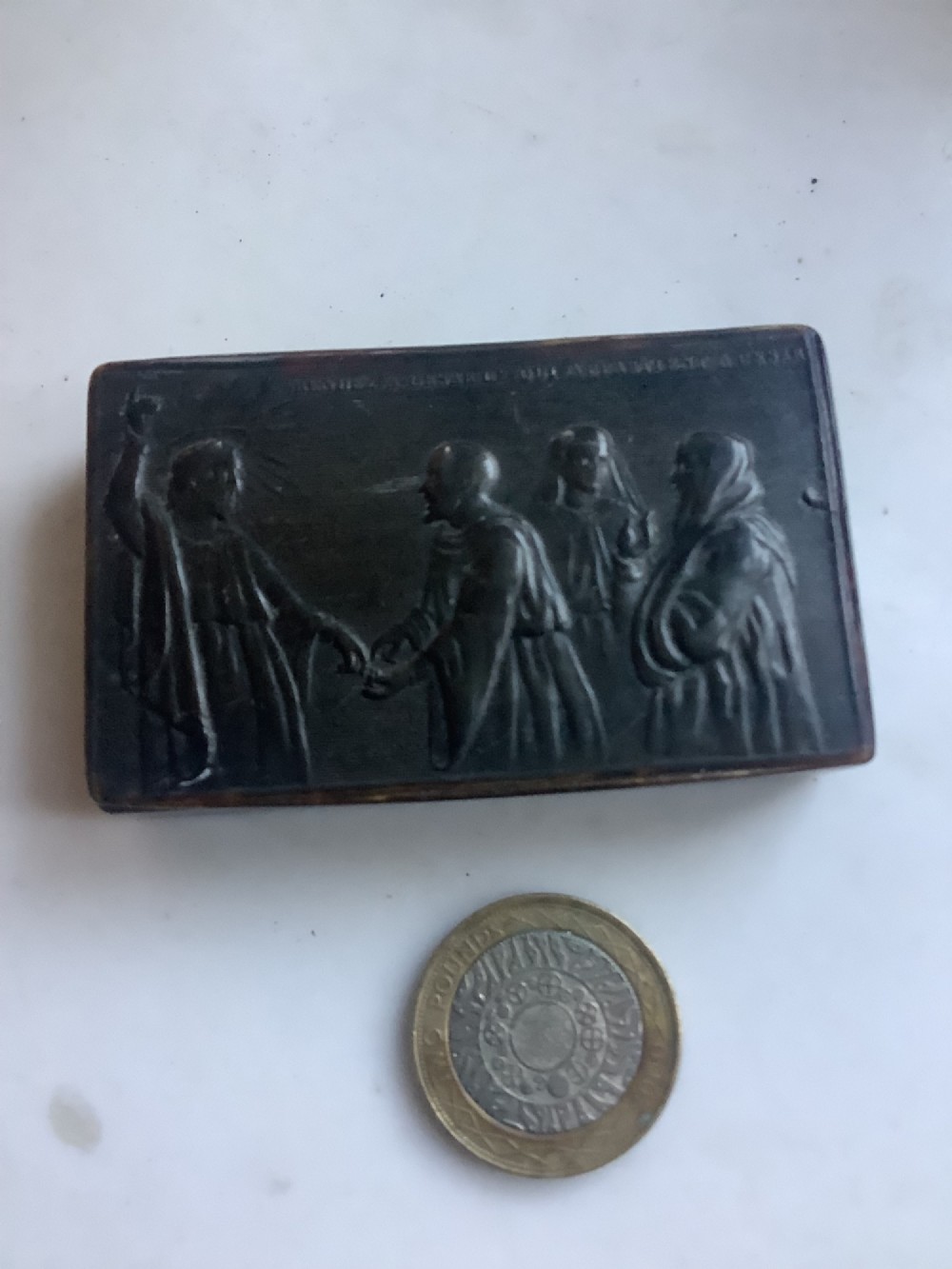 A rectangular dark brown pressed horn snuff box displaying a moulded relief of a biblical scene with figures and a French inscription on the top lid. View VIII
