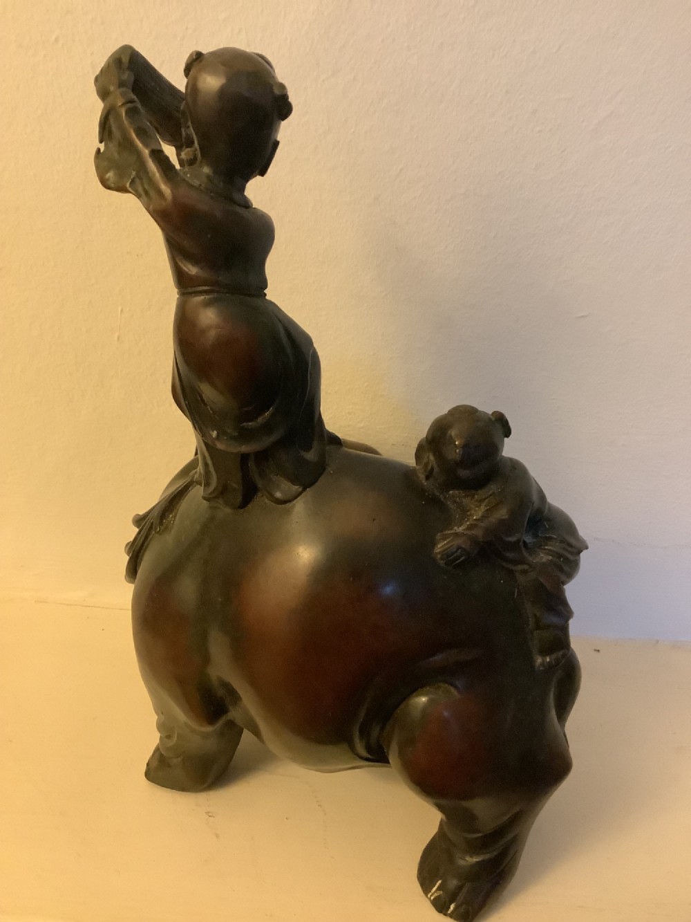 A dark brown patinated bronze sculpture depicting an elephant with two young boys on its back. View II