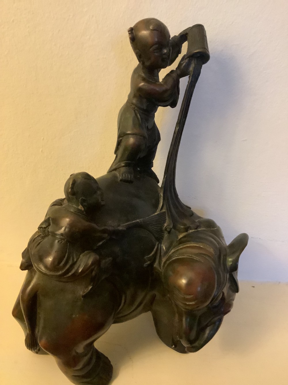 A dark brown patinated bronze sculpture depicting an elephant with two young boys on its back. View V