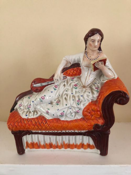 a staffordshire figure of a lady reclining on a chaise longue with a mandolin in one hand and a book in another - CATEGORY: ANTIQUE CERAMICS - DATED 1860
