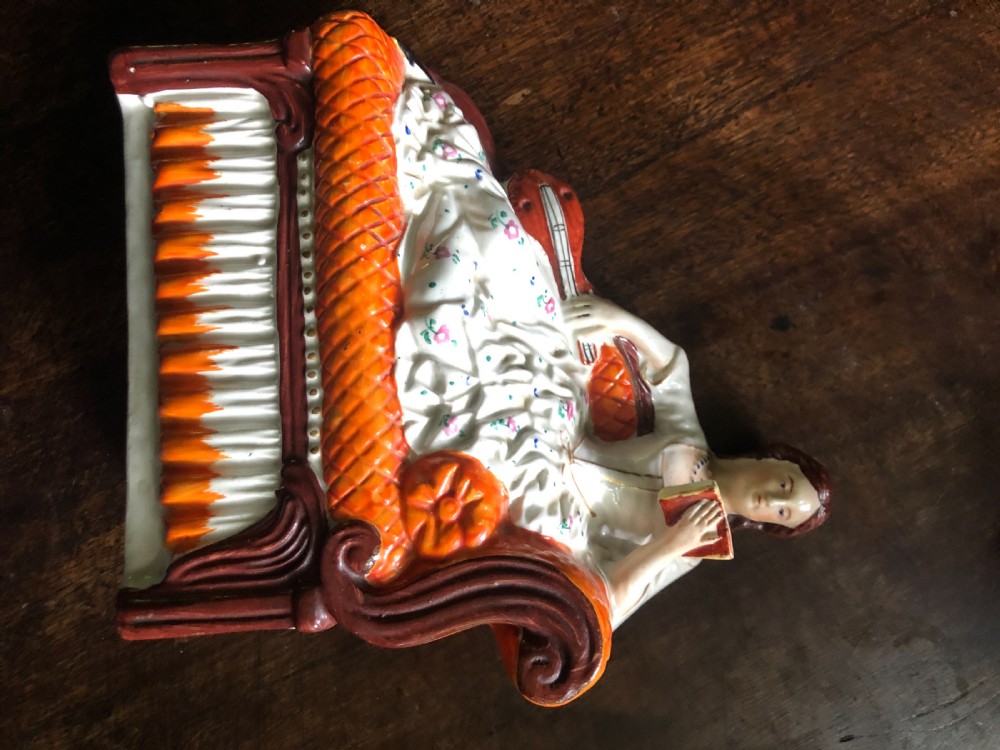 A Staffordshire Figure of a Lady reclining on a chaise longue with a mandolin in one hand and a book in another. View VI