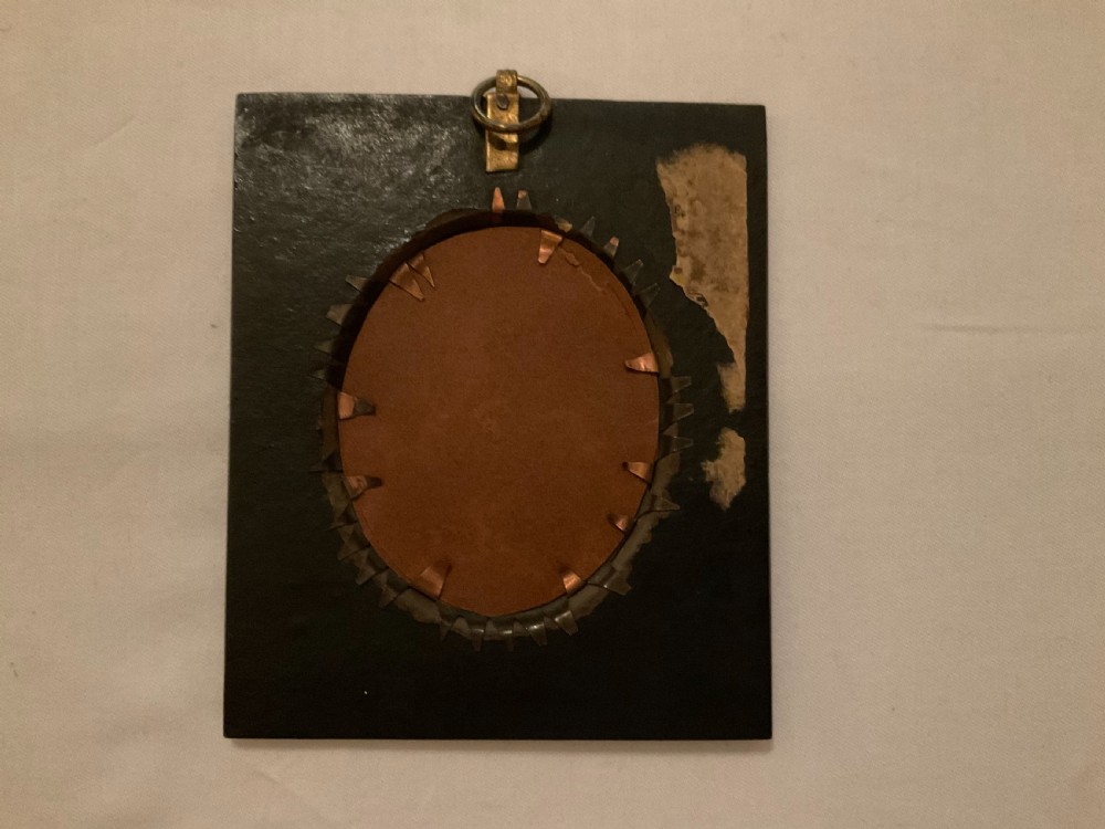 A mid-nineteenth century watercolour profile portrait of a young lady set within an oval brass bezel and black rectangular ebonised frame with a top acorn hanger. View II