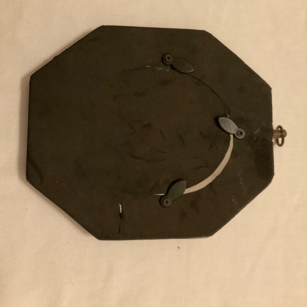 A nineteenth-century black profile silhouette portrait of a gentleman in formal dress framed in an oval gilt bezel within a black octagonal frame with a brass acorn hanger. View II