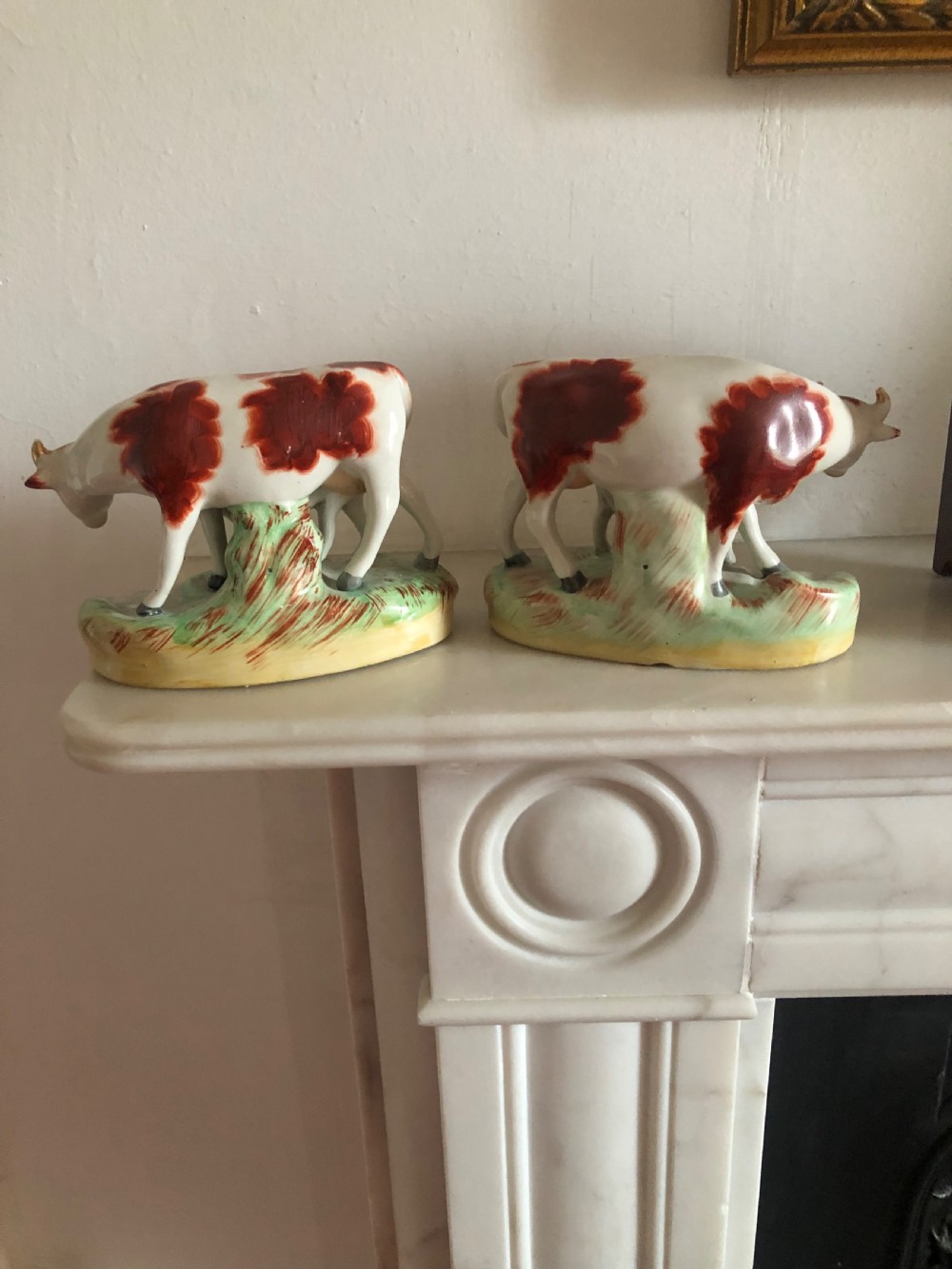 A pair of nineteenth-century earthenware Staffordshire figures featuring red and white cows standing alongside their calves on oval green grass bases. View II