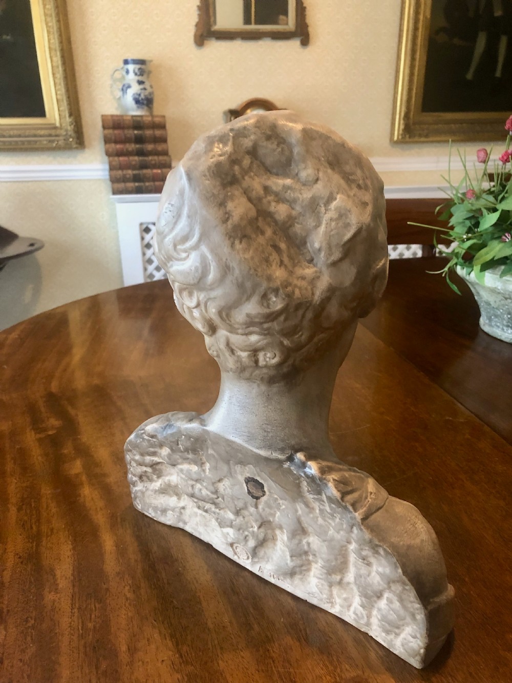 A 19th-century terracotta-style sculptural bust depicting a youth with curled hair and draped garments looking downwards. View IX