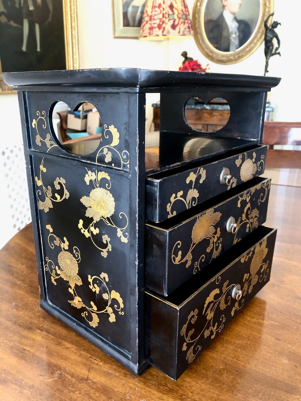 A Japanese black lacquer table cabinet featuring three decorated drawers, an open upper shelf, and gold floral chrysanthemum motifs. View VII