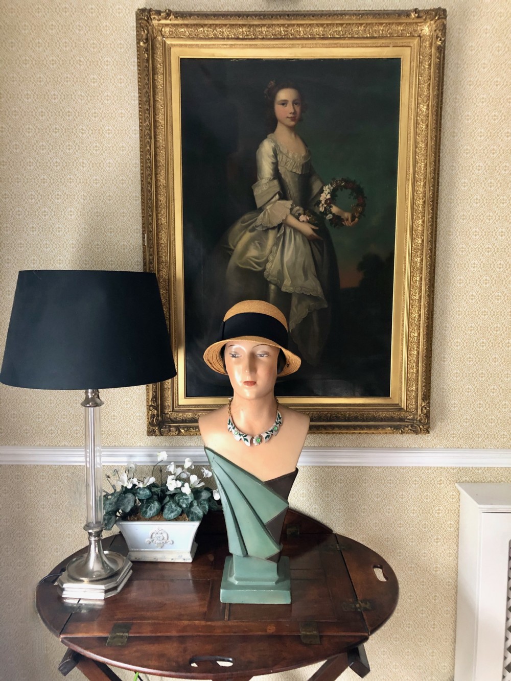A 1930s French Art Deco painted plaster mannequin bust featuring a green draped base and hand-painted facial details.