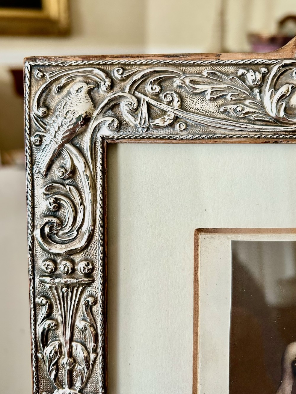 A rectangular Edwardian sterling silver picture frame featuring elaborate embossed scrollwork, foliate patterns, and mythical motifs surrounding a central portrait print. View III