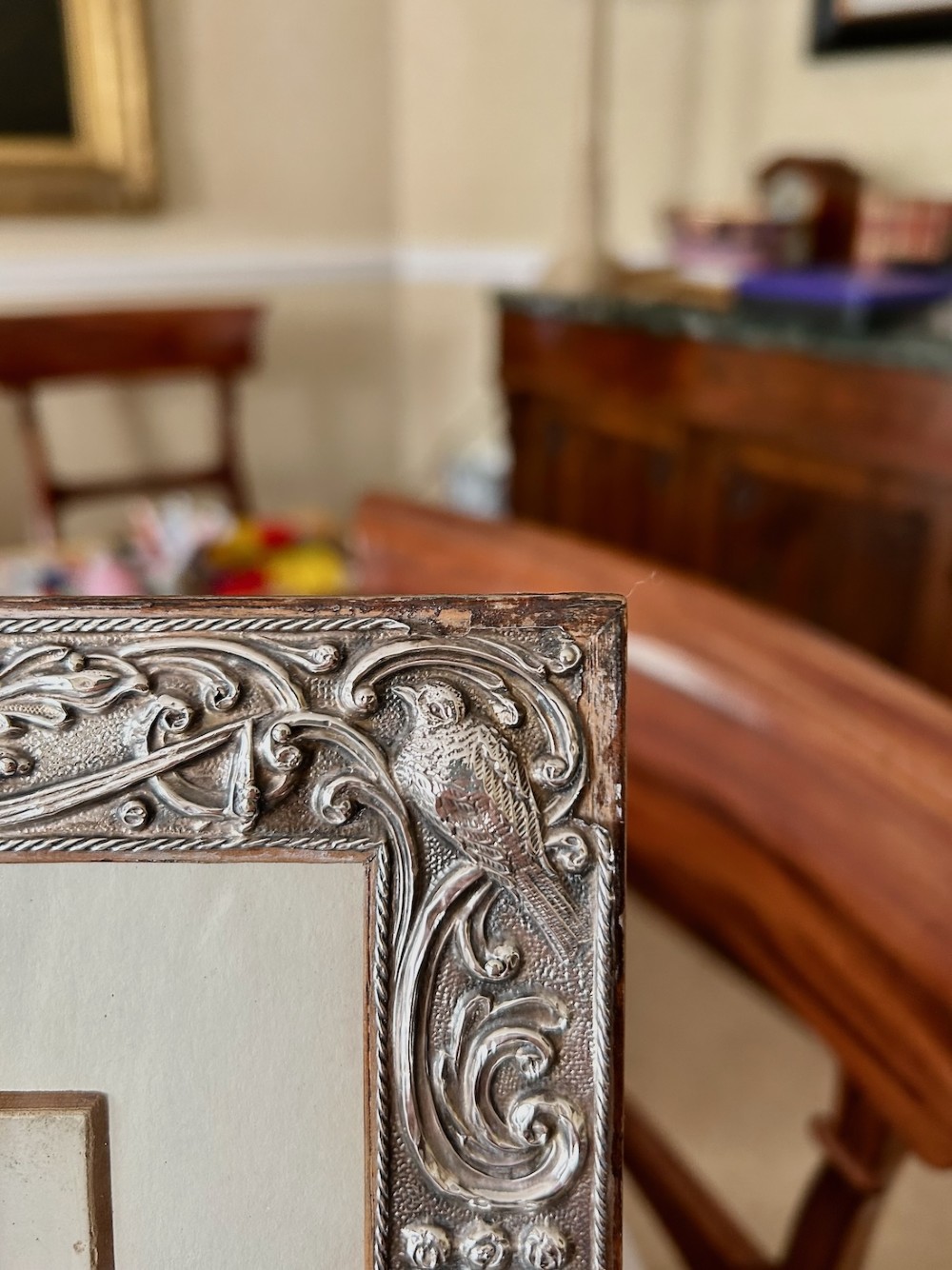 A rectangular Edwardian sterling silver picture frame featuring elaborate embossed scrollwork, foliate patterns, and mythical motifs surrounding a central portrait print. View IV