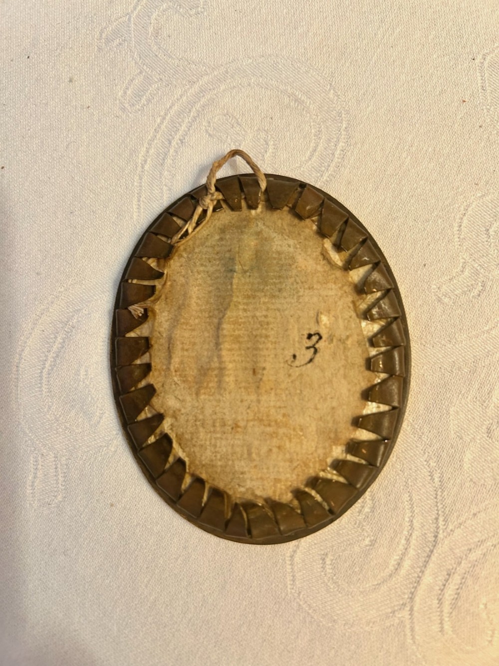 An oval Georgian portrait miniature depicting a woman wearing a laced veil set inside a narrow gilt metal frame with a suspension loop. View III