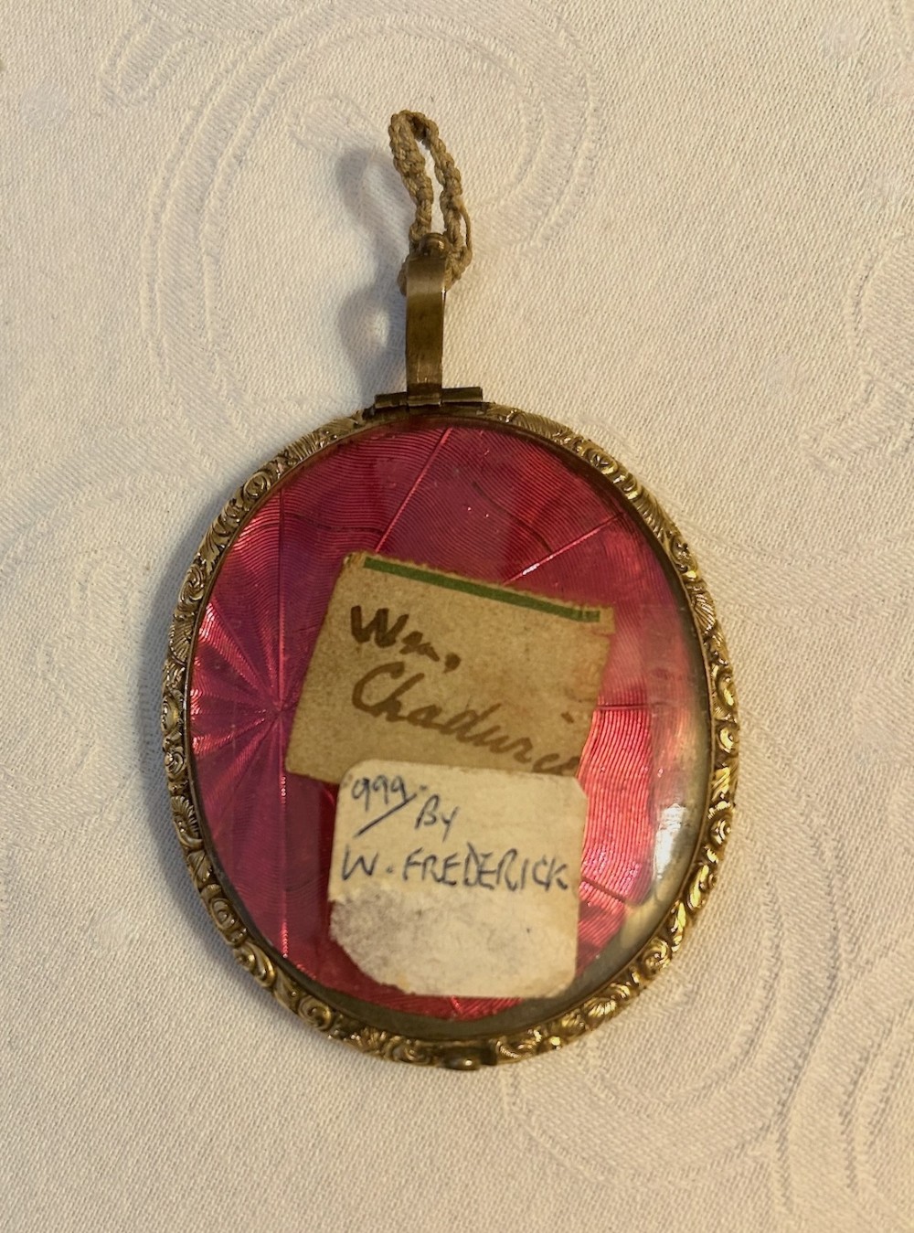 An oval Georgian portrait miniature painting depicting a gentleman with dark hair and a white cravat, housed in a chased gilt-metal frame with a top suspension loop. View II