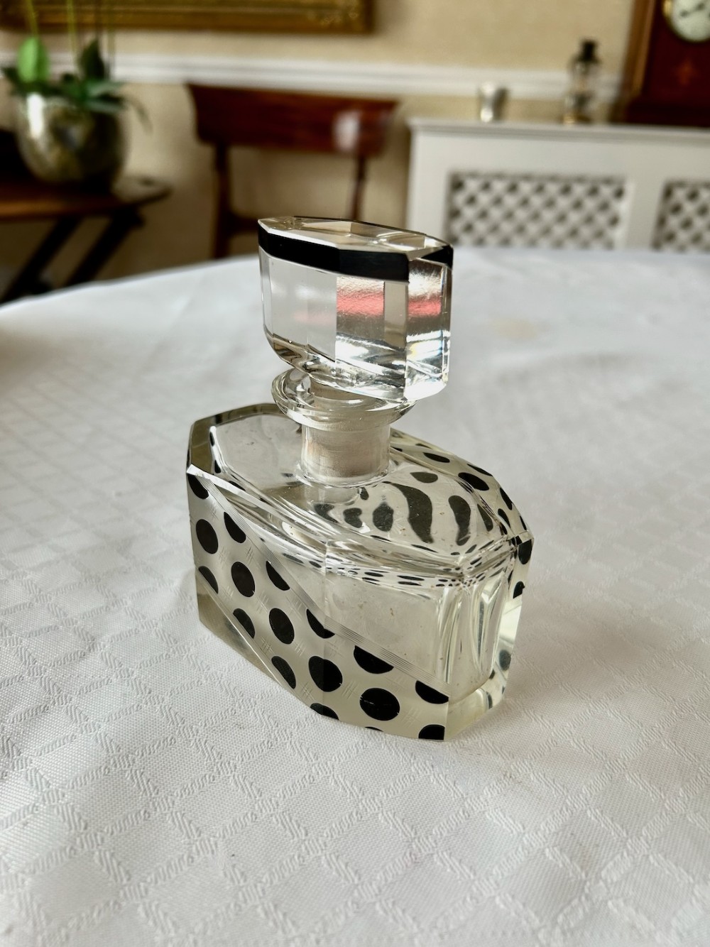 An Art Deco clear glass scent bottle featuring black polka dots across a diagonal band with a faceted geometric cut stopper. View II