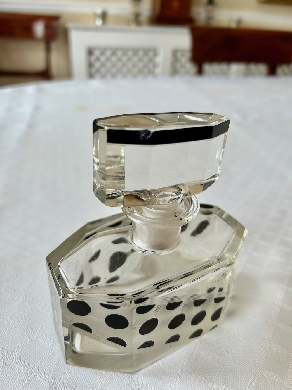 An Art Deco clear glass scent bottle featuring black polka dots across a diagonal band with a faceted geometric cut stopper. View III