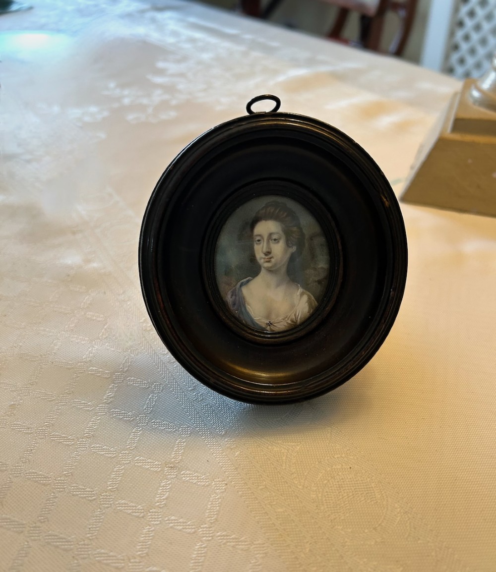 An 18th-century oval portrait miniature depicting a lady in a blue drape, housed within a circular ebonised wood frame with a top metal suspension loop. View III