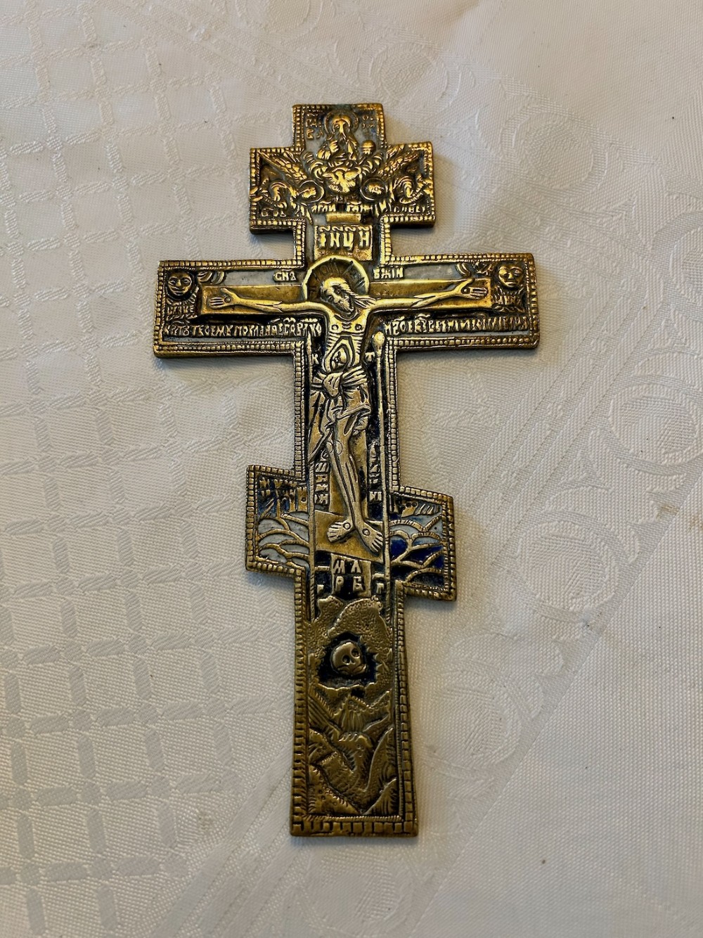A 19th-century cast bronze Russian Orthodox eight-pointed cross featuring inlaid blue and white enamel detailing and Cyrillic inscriptions.